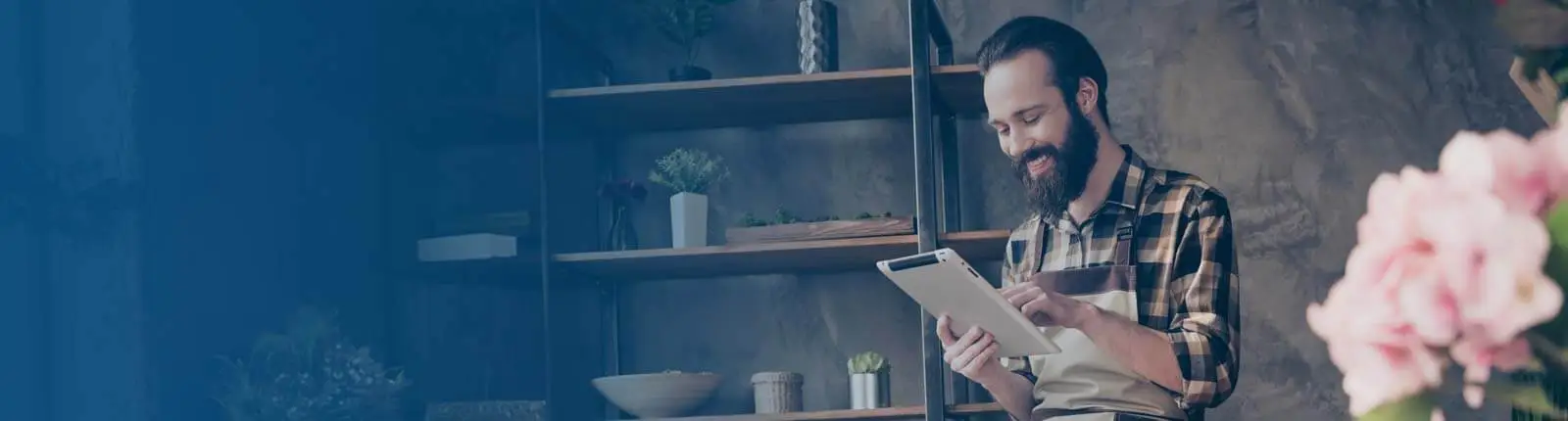 Smiling bearded man in a plaid shirt looking at his WebWyze marketing results on a tablet.